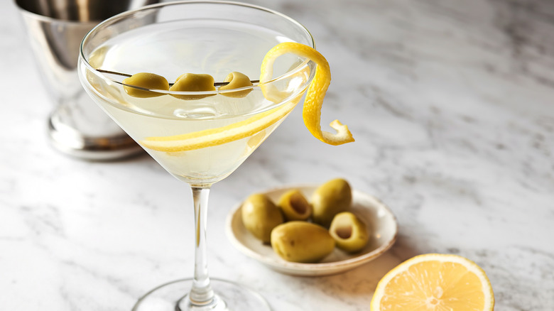 A Martini garnished with olives and a lemon peel