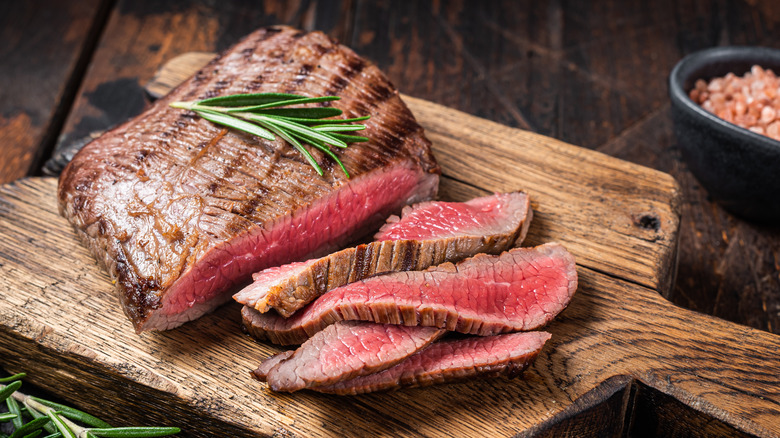flank steak on wood board with rosemary