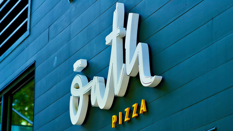 Oath Pizza store sign on black building panels