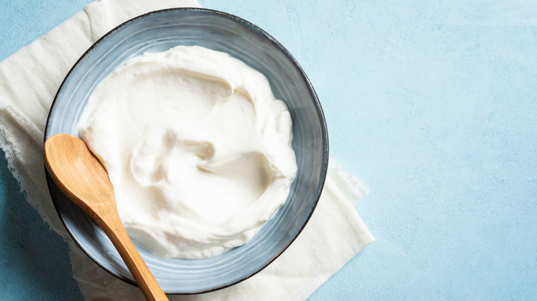 Homemade Greek yogurt in a bowl with a wooden spoon