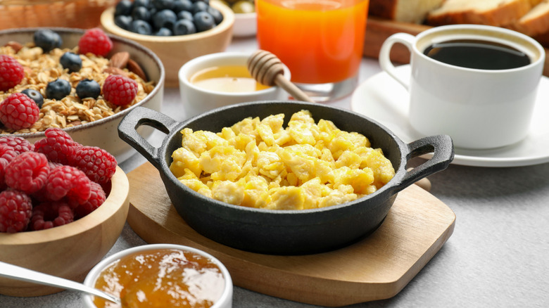 A skillet of scrambled eggs surrounded by other breakfast foods