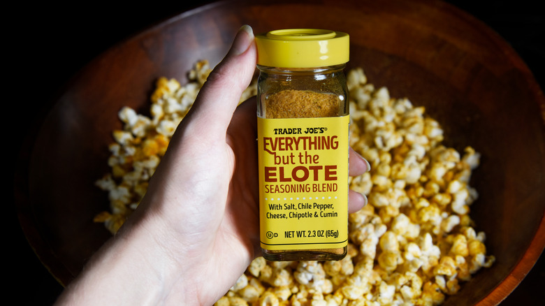 popcorn seasoned with everything but the elote and hand holding jar