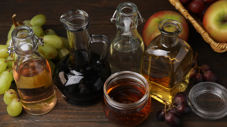 Different types of vinegars and fresh fruits on a table