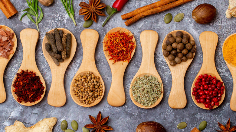 Various whole spices on wooden spoons