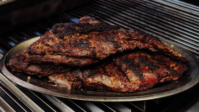 Well done, charred beef resting on a grill