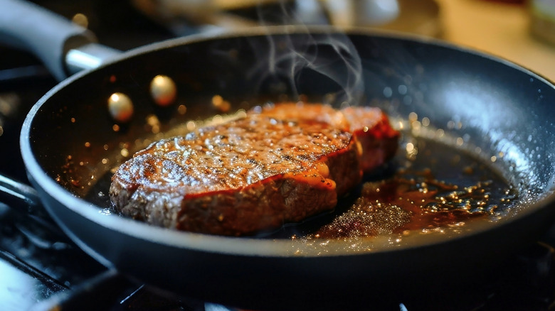 A lean steak searing in a piping hot pan