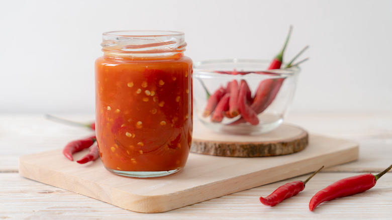 Sweet chili sauce in glass jar on cutting board