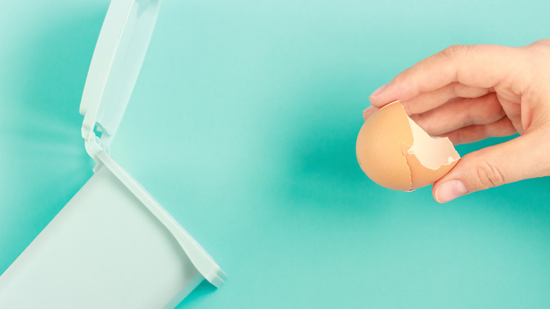 Hand throwing eggshells in trashcan