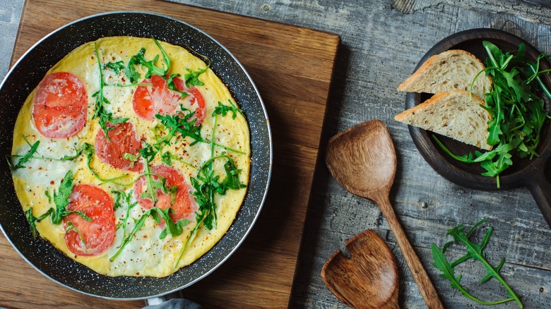 omelet with tomatoes in frying pan