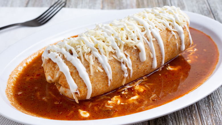 Burrito with red sauce and cheese on top