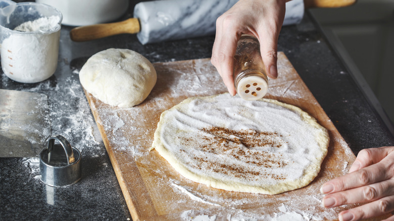 Baker using cinnamon on dough