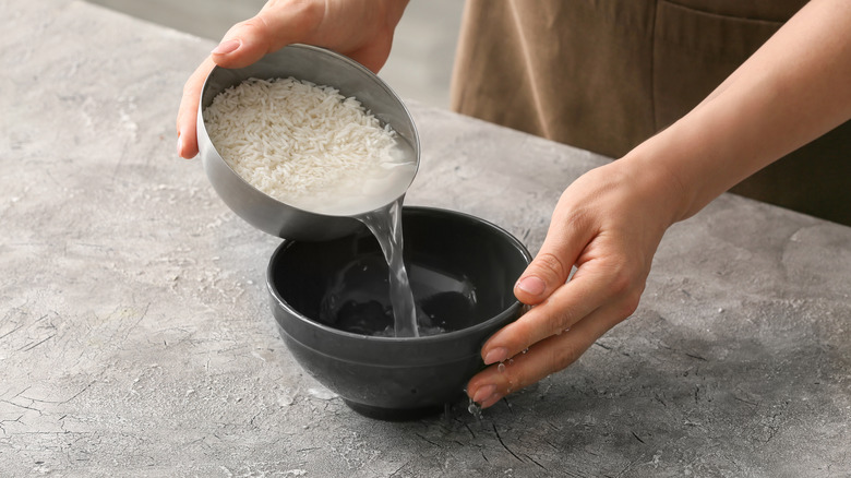 Person rinsing rice using two bowls