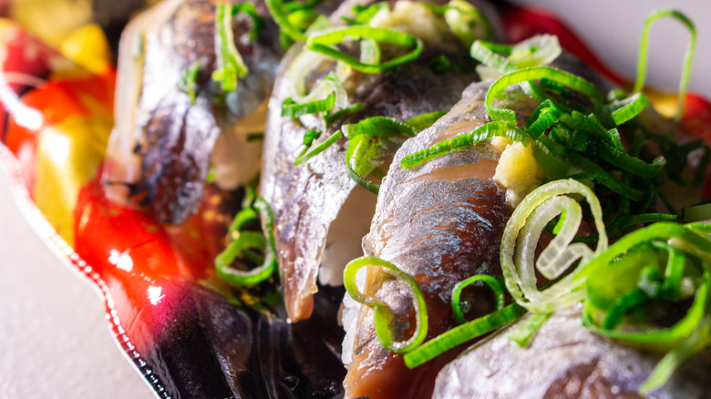 horse mackerel sushi garnished with thinly sliced scallion on a platter