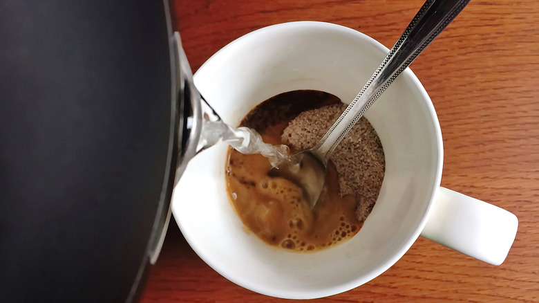 Pouring water into mug with instant coffee