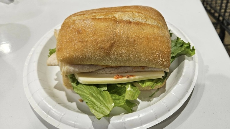 The Costco Turkey & Swiss sandwich sits on a plate in the food court