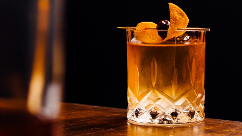 Old fashioned whiskey cocktail garnished with orange peel and a cherry