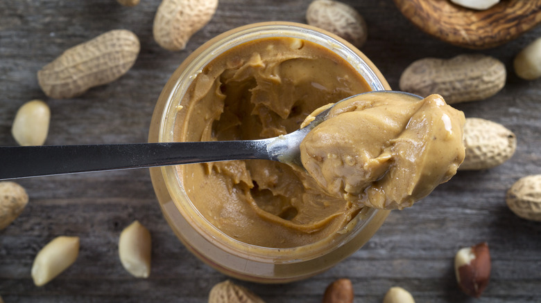 Spoon of peanut butter being lifted from jar 