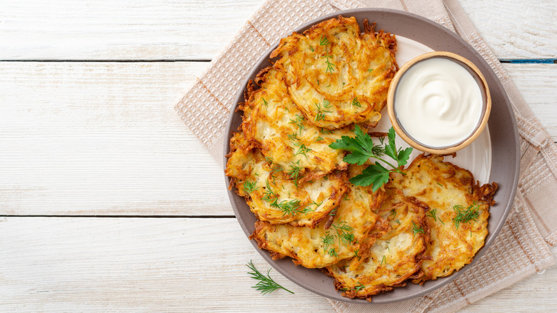 Latkes on a plate with sour cream on the side