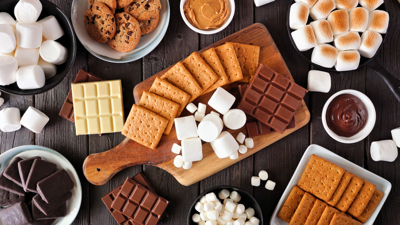 ingredients for s'mores in bowls and on plates and wooden cutting board