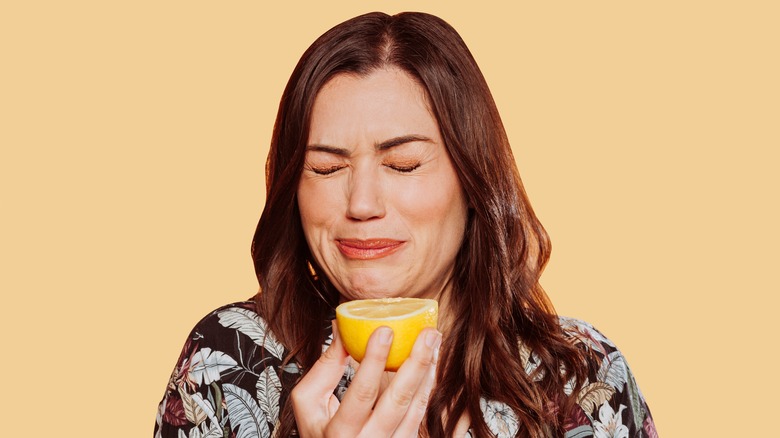 woman eating lemon with scrunched face