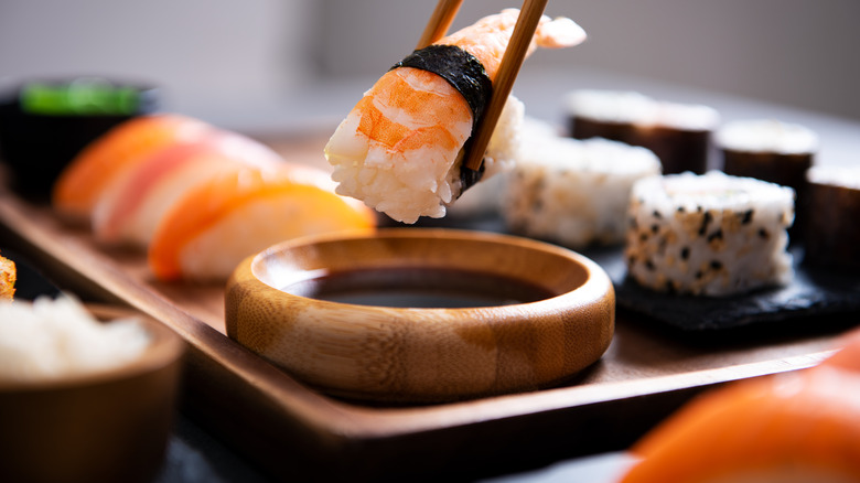 closeup of plate of sushi and piece held with chopsticks