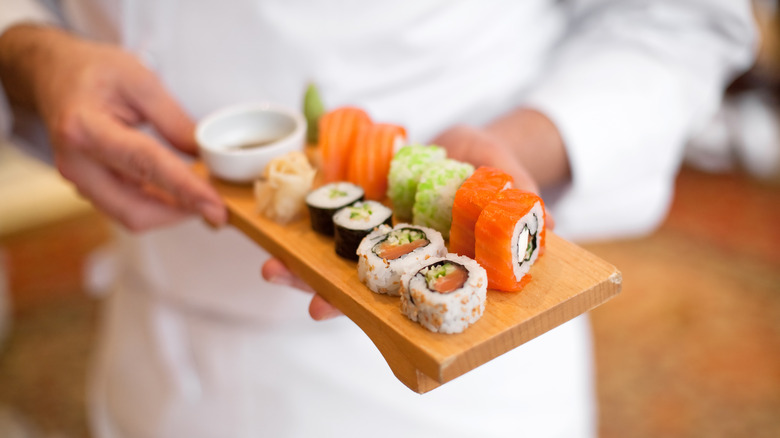 sushi chef holding platter of sushi