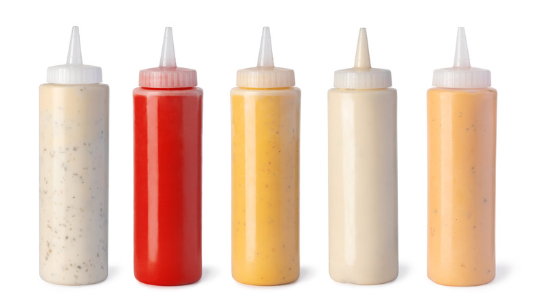 squirt bottles with assorted sauces on white background