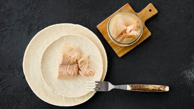 Canned trout has been transferred from an open can to a white plate