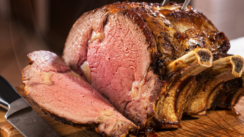 Cooked standing rib roast sliced on a wooden board