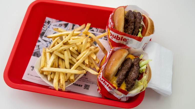 Two In-N-Out double-double burgers plus fries rest on a red tray