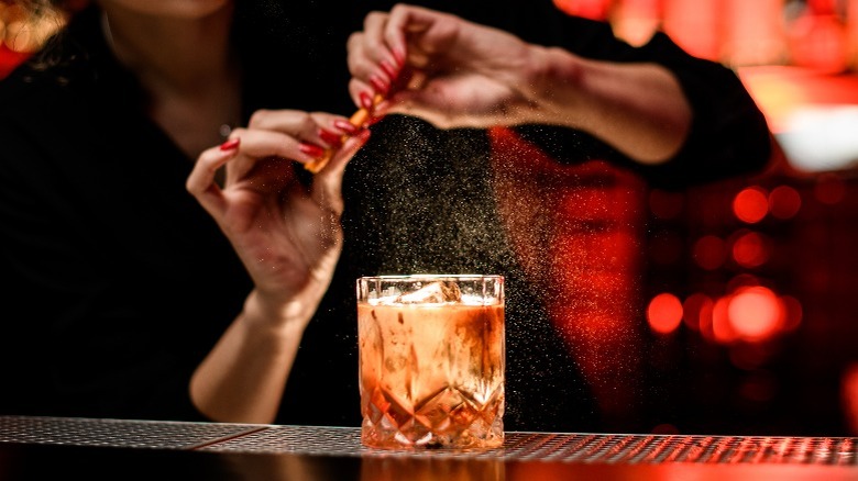A bartender garnishing an Old Fashioned cocktail