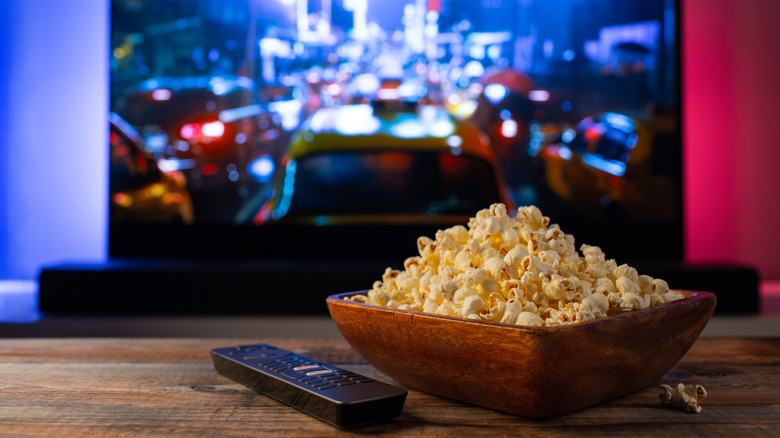A bowl of popcorn in front of a television 