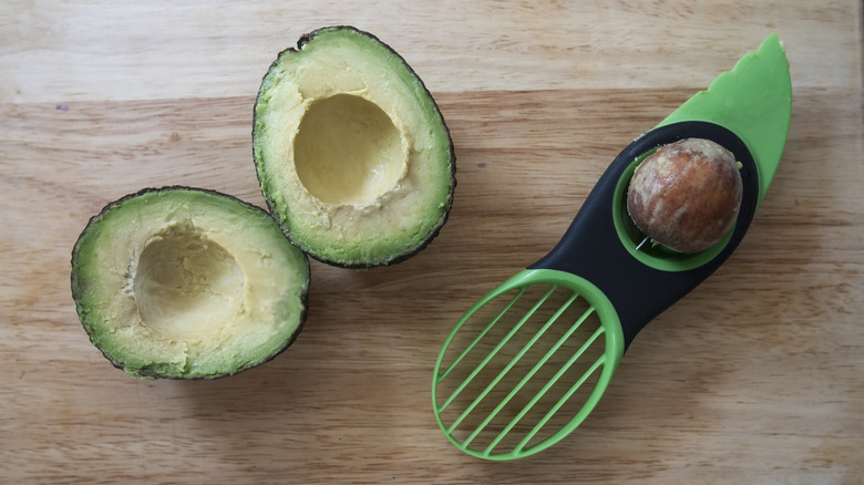 Sliced avocado on table next to avocado slicer