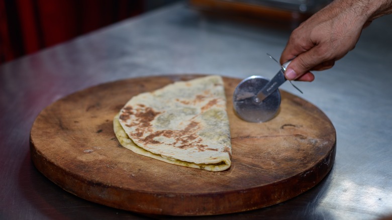 pizza wheel cutting through tortilla