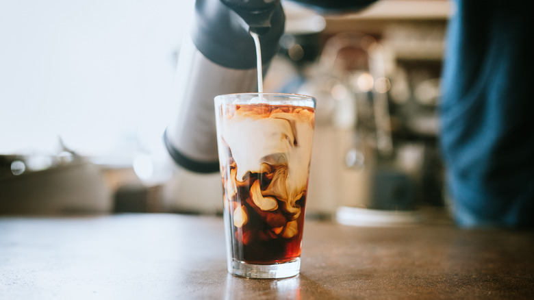 Pouring milk into iced coffee