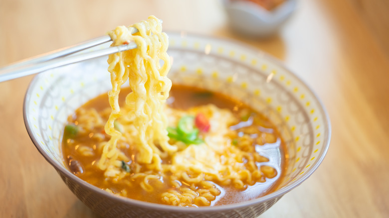 spicy ramen with cheese in a bowl, with chopsticks