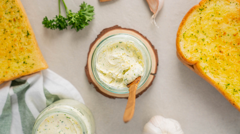 Jar of infused butter with a spoon inside of it next to toast