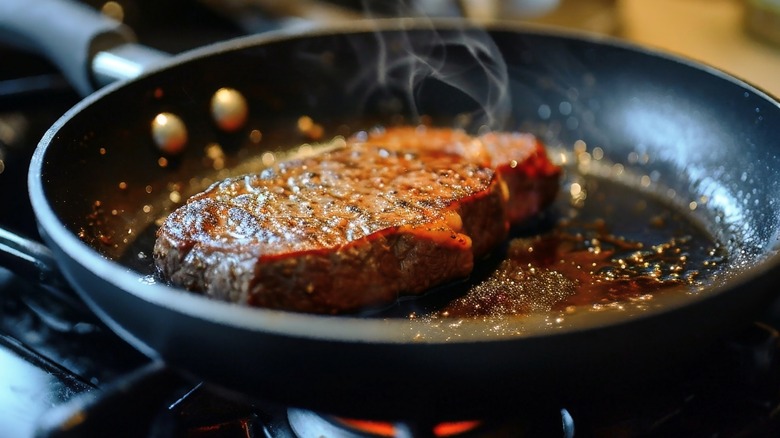 Steak being seared in a hot pan