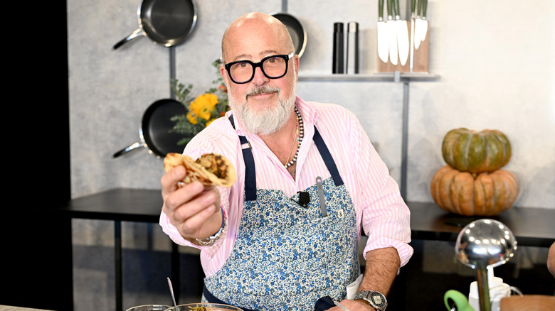 Andrew Zimmern smiling and presenting food at live appearance