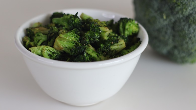 Saureed broccoli in a white bowl with raw broccoli in the background