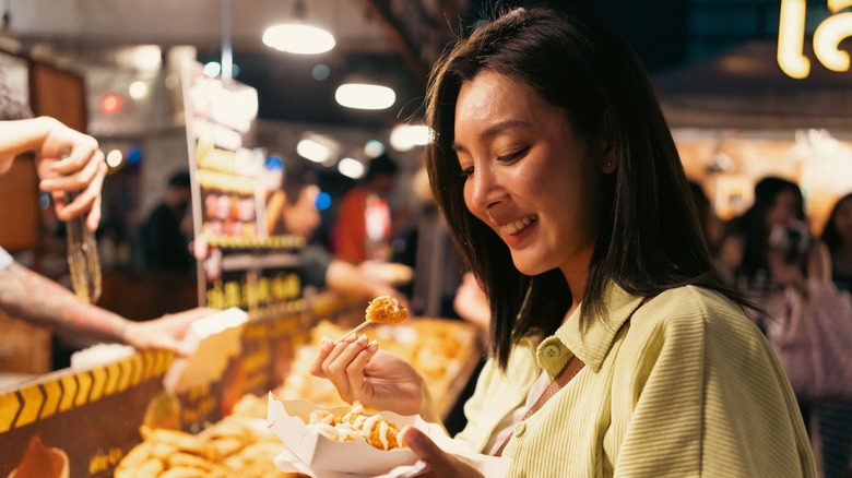 Person eating street food at outdoor market