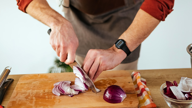 Man slicing onions with curled fingers and sharp knife