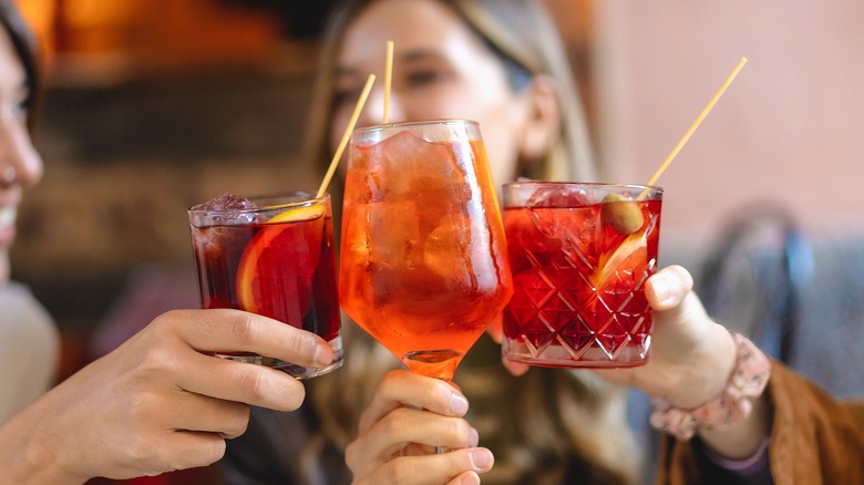 a group cheers with aperol spritzes