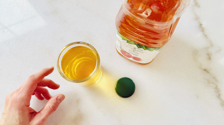 Reaching for apple juice in glass near jug of juice on a table