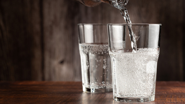 Two glasses of fizzy liquid in picardie glasses with liquid being poured into the front glass