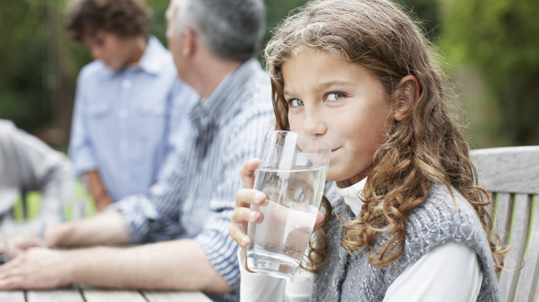 Child drinking water at picnic table