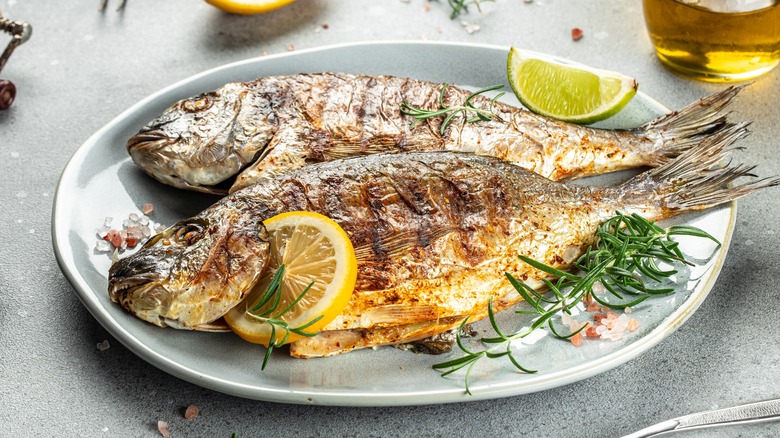 Grilled whole fish on plate with lemon