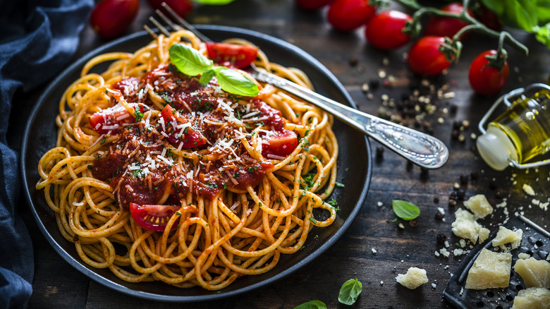 Spaghetti pasta with tomato pomodoro sauce on plate with fork and fresh basil