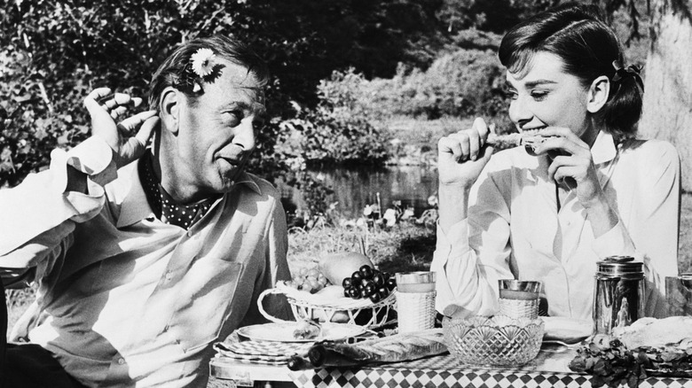 Audrey Hepburn and Gary Cooper eating a picnic meal