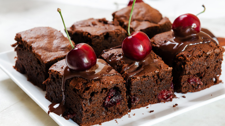 Brownies with chocolate sauce and cherries inside and on top